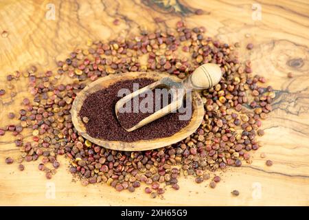 sizilianische Sumach (Rhus coriaria), getrocknete Sumaksamen, ganz und mit einer Schaufel auf einer Holzplatte gemahlen Stockfoto