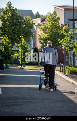 Älterer Mann, der allein draußen mit einem Rollator läuft Stockfoto