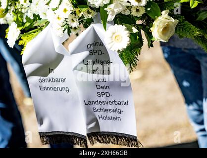 Kiel, Deutschland. Juli 2024. Die Aufschrift "in dankbarem Gedenken - Ihre SPD-Landtagsfraktion und Ihr SPD-Landesverband Schleswig-Holstein" steht auf Bändern auf einem Kranz, der am Grab der ehemaligen Schleswig-holsteinischen Ministerpräsidentin Heide Simonis zum ersten Todestag gelegt wurde. Die Führer der nördlichen SPD und der Witwer trafen sich am Grab. Quelle: Axel Heimken/dpa/Alamy Live News Stockfoto