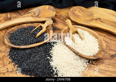 sesamum, Sesam (Sesamum indicum), geschälte und ungeschälte Sesamsamen mit Holzlöffeln und Holzlöffeln Stockfoto