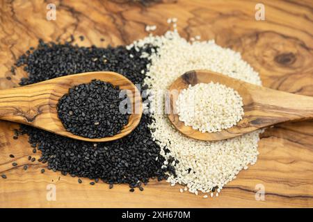 sesamum, Sesam (Sesamum indicum), geschälte und ungeschälte Sesamsamen mit Holzlöffeln Stockfoto
