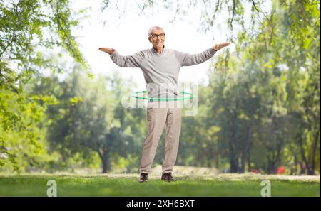 Ein älterer Herr spinnt einen Hula Hoop in einem Park Stockfoto