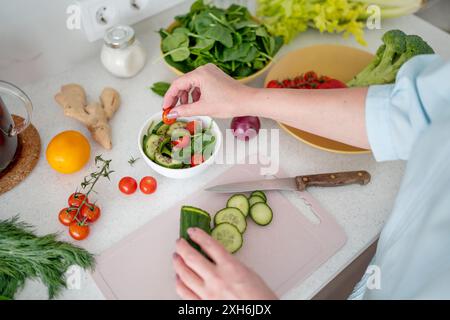 Eine Frau wird von oben gesehen, die eine Gurke in einer Mischung aus frischem Gemüse schneidet Stockfoto