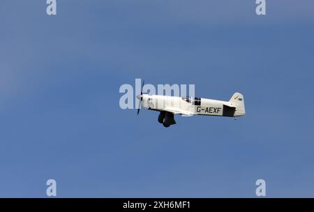 1936 Percival Mew Gull G-AEXF Flugzeuge im Flug mit blauem Himmel und Wolken. Stockfoto