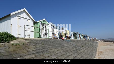 Strandhütten an der erhöhten Promenade mit Urlaubern, die Sonnenschein genießen. Stockfoto