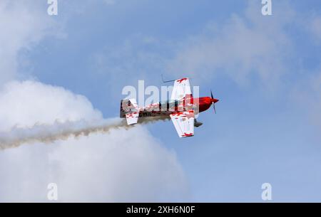 Global All Stars Extra 300S Stuntflugzeug im Flug mit Rauch Stockfoto