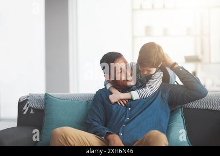 Vater, Junge und Umarmung auf dem Sofa für Unterstützung zu Hause, Bindungen und entspannende Gespräche. Daddy, Sohn und willkommen mit glücklicher Familie für die Liebe im Wohnzimmer Stockfoto