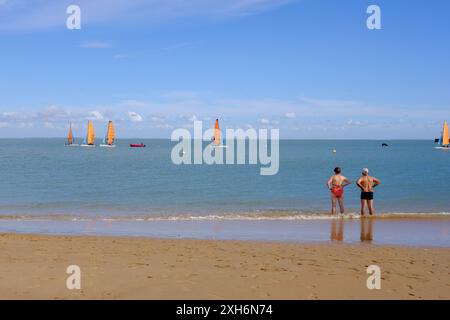 Ein Paar beobachtet die Segelboote in Plage de la Boyardville, Oleron Island. Stockfoto
