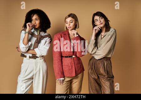 Eine vielfältige Gruppe stilvoller junger Frauen verschiedener Kulturen steht auf beigefarbenem Hintergrund zusammen. Stockfoto