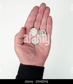 Hand eines kaukasischen Mannes mit drei US-25-Cent-Münzen Stockfoto