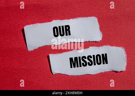 Unsere Botschaft auf gerissenem weißem Papier mit rotem Hintergrund. Konzeptionelles unser Missionssymbol. Kopierbereich. Stockfoto