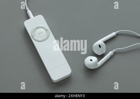 Ein Apple iPod Shuffle 1st Generation (2005) mp3-Player mit Ohrhörern auf grauem Hintergrund Stockfoto