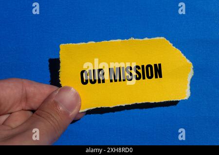 Unsere Botschaft auf gerissenem gelbem Papier mit blauem Hintergrund. Konzeptionelles unser Missionssymbol. Kopierbereich. Stockfoto