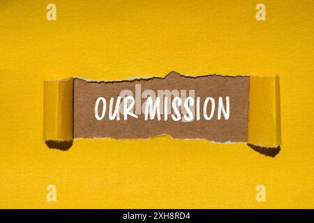 Unsere Botschaft auf gerissenem gelbem Papier mit braunem Hintergrund. Konzeptionelles unser Missionssymbol. Kopierbereich. Stockfoto