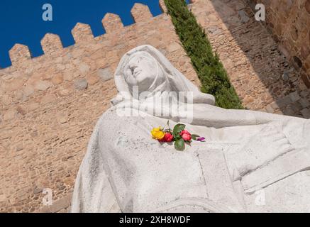 Spanien, Kastilien und Leon, Avila, Stadtmauern, die ab 1090 erbaut wurden und zu den am besten erhaltenen und vollständigsten in Europa gehören, mit einer weißen Statue der Heiligen Teresa von Avila im Vordergrund. Stockfoto