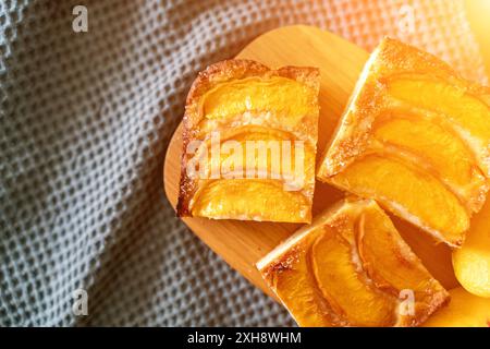 Ein Dessert aus geschnittenen Pfirsichen ist auf einem hölzernen Schneidebrett. Das Dessert ist mit Zucker bedeckt und sieht köstlich aus. Stockfoto