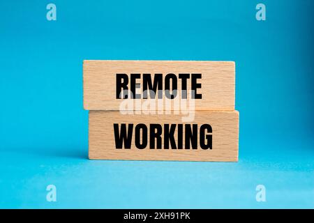 Meldung über die Fernbedienung auf Holzblöcken mit blauem Hintergrund. Konzeptionelles Symbol für Remote Working. Kopierbereich. Stockfoto
