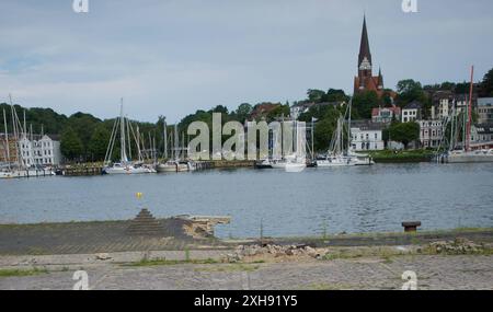 Flensburg, Schleswig-Holstein Dampfrundum 2024 Flensburg, die Veranstaltung wird 2024 aufgrund der Schäden durch das Ostseesturmhochwasser im Oktober 2023 an einem zwei Orten stattfinden. Die Organisatoren müssen auf den angestammten Platz an der südlichen Schiffbrücke verzichten, da die Kaikante dort abgesackt ist. Eine Absperrung wurde errichtet, hier: Blick von der Westseite des Flensburger Hafens zur Ostseite über das Hafenbecken. Weiter im Bild Asphalt-Steine werden zu kunstvoll anmutenden Aufbauten gestapelt. Aufnahme vom 12.07.2024, Flensburg, Hafen West *** Flensburg, Schleswig Holstei Stockfoto