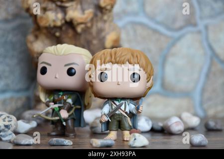 Funko Pop Actionfiguren von Elf Legolas und Hobbit Sam aus dem Fantasy-Film der Herr der Ringe. Krieger halten Schwert, Bogen und Pfeil, Baum, Steine. Stockfoto