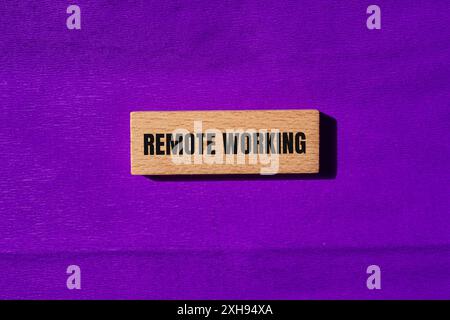 Meldung über die Fernbedienung auf Holzblöcken mit violettem Hintergrund. Konzeptionelles Symbol für Remote Working. Kopierbereich. Stockfoto
