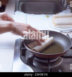 Zubereitung von frittierten Tacos in einer Pfanne, Sie können nur einige Hände sehen, die einige Tacos in die Pfanne geben, traditionelle mexikanische Küche. Stockfoto