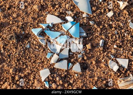 Hellblaue und weiße Keramikfliesen, die in kleine scharfe Stücke zerbrochen sind und in der Natur auf den vulkanischen Boden geworfen werden. Lanzarote, Kanarische Inseln, Spanien. Stockfoto