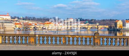 Blick auf die Karlsbrücke in Prag, Tschechien, von der Legionsbrücke. Die Brücke, gesäumt von historischen Gebäuden, überspannt die Moldau. Das Wasser reflektiert den blauen Himmel und die umliegende Stadtlandschaft. Stockfoto