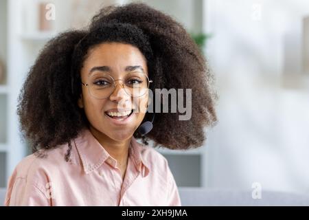 Porträt einer lächelnden Frau mit Brille und Headset, die von zu Hause aus arbeitet. Konzept der Fernarbeit und des Kundenservice Stockfoto