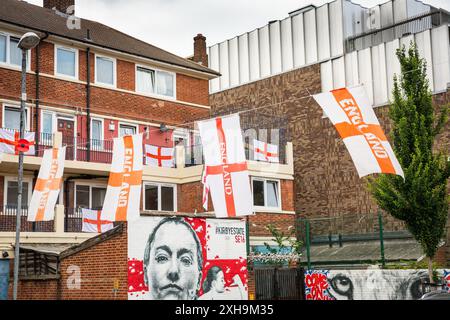 Bermondsey, London, 12. Juli 2024. Das Kirby Estate in Bermondsey, bekannt für seine farbenfrohen Flaggendekorationen für Fußballspiele Englands, ist wieder einmal mit mehreren hundert Flaggen auf dem patriotischen Anwesen, sowie dem kürzlich enthüllten Wandgemälde von Eberechi Eze und anderen farbenfrohen Wandgemälden in den Rillen, vor dem Finale der Fußball-Europameisterschaft England gegen Spanien am Sonntag. Quelle: Imageplotter/Alamy Live News Stockfoto