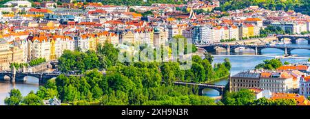 Ein malerischer Blick auf die Moldau, die sich durch das Herz von Prag schlängelt, Tschechien. Mehrere berühmte Brücken, darunter die Karlsbrücke, überqueren den Fluss. Die farbenfrohen Gebäude und das üppige Grün der Stadt bilden eine atemberaubende Kulisse. Stockfoto