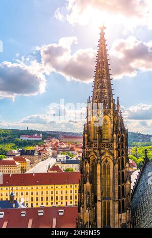 Der verzierte Seitenturm des Veitsdoms überragt die umliegende Landschaft mit Stadt und Grün im Hintergrund unter teilweise bewölktem Himmel. Stockfoto