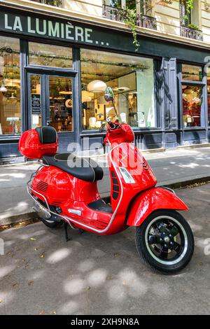 Roter Vespa-Roller parkt auf dem Boulevard Raspail, Paris 75014, Frankreich. Stockfoto