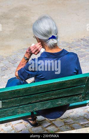 Reife Frau saß auf der Parkbank und las auf dem Square Boucicaut, Paris 75007, Frankreich. Stockfoto