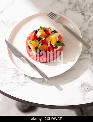 Wunderschön präsentiertes Obstdessert mit frischen Beeren und essbaren Goldflocken. Stockfoto