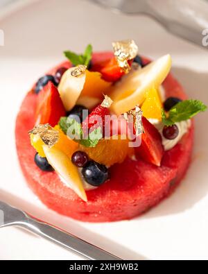 Frisches und gesundes Obstdessert garniert mit Beeren und Goldflocken, perfekt für einen Gourmet-Genuss. Stockfoto