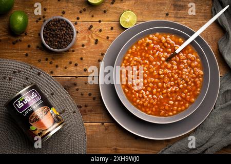 Köstliche und herzhafte Schüssel Linsensuppe mit frischer Limette und schwarzem Pfeffer auf einem rustikalen Holztisch. Stockfoto