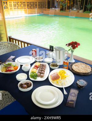 Köstliche iranische Küche am Pool mit Kebabs, Safranreis, frischem Salat und traditionellem Brot Stockfoto