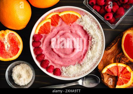 Raspberry Orange Smoothie Bowl garniert mit Kokos: Rosafarbene, glatte Schüssel garniert mit Himbeeren, Orangenscheiben und Kokosraspeln Stockfoto