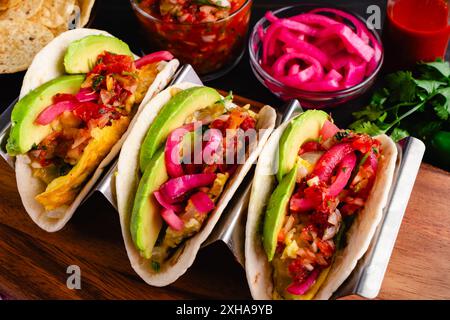 Tex-Mex Migas Frühstück Tacos in einem Taco Halter: Blick von oben auf Frühstückstakos mit Eiern, geschnittener Avocado, eingelegten Zwiebeln und Salsa Stockfoto