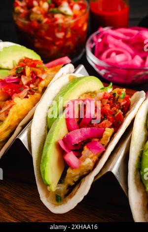 Tex-Mex Migas Frühstück Tacos in einem Taco Halter Nahaufnahme: Blick über dem Kopf auf Frühstückstakos mit Eiern, geschnittener Avocado, eingelegten Zwiebeln und Salsa Stockfoto