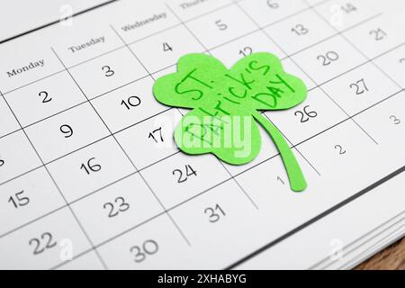 Papier Kleeblatt mit den Worten ST. PATRICKS TAG und Kalender auf Holzhintergrund Stockfoto
