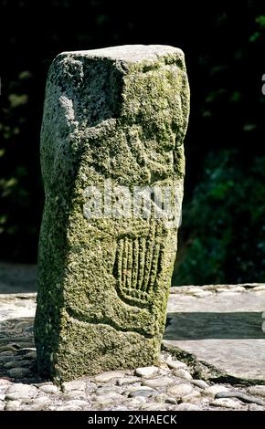 Mann spielt keltische Klarsach Harfe auf einem von zwei geschnitzten Steinen, die das frühchristliche Carndonagh Cross, Co. Flankieren. Donegal, Irland Stockfoto