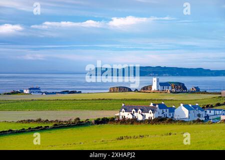 Ballintoy Pfarrkirche in Ballintoy Harbour in der Nähe von Bushmills an County Antrim Coast Road. Rathlin Insel hinter. Nordirland Stockfoto