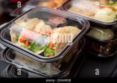 Ein Blick auf mehrere Hauptgerichte, die in Plastikbehältern für unterwegs zubereitet werden, die zum Mitnehmen bereit sind, in einem Restaurant. Stockfoto