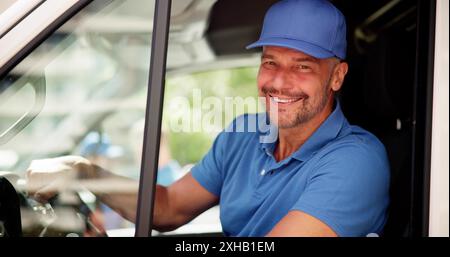 Die Erfüllung der Logistik: Ein lächelnder Fahrer in einem einheitlichen Lieferwagen für effizienten Supply Chain Service Stockfoto