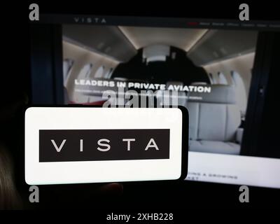 Person, die ein Smartphone mit dem Logo der Emirati Aviation Company Vista Global Holding Limited vor der Website hält. Schwerpunkt auf dem Display des Telefons. Stockfoto