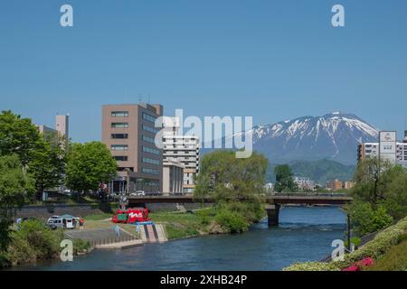 Genießen Sie die ruhige Schönheit von Morioka von der Kaiun-Brücke aus: Ein atemberaubender Blick auf den Mount Iwate mit seinem schneebedeckten Gipfel, dem klaren blauen Himmel und den Bergen Stockfoto