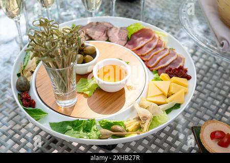 Eine kunstvoll gestaltete Wurstplatte mit einer Auswahl an Wurstwaren, Käse, Oliven, Artischocken und Crackern. Perfekt für anspruchsvolle Stockfoto