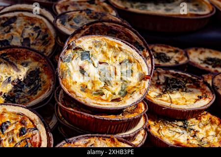 Leckeres vegetarisches Streetfood zum Mittagessen in London, verschiedene Quiche herzhafte Tarte mit Spinat, Tomaten, Pilzen, Cheddar-Käse, Nahaufnahme Stockfoto