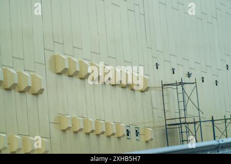 Ein großes Gebäude mit vielen Fenstern und Lüftungsschlitzen. Das Gebäude ist gelb und hat viele Fenster. Stockfoto